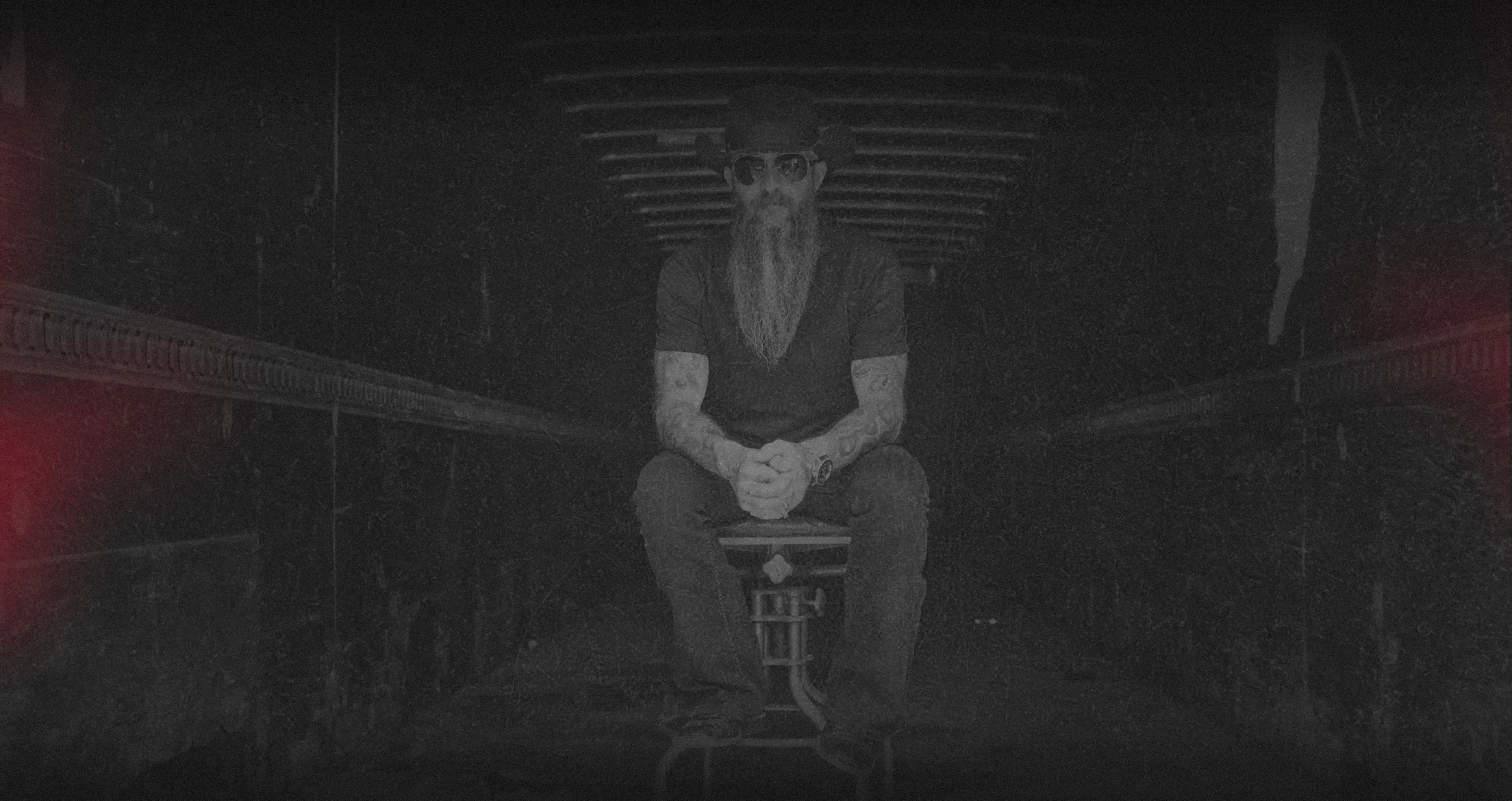 Photo of Cody Jinks sitting on a stool in a tunnel
